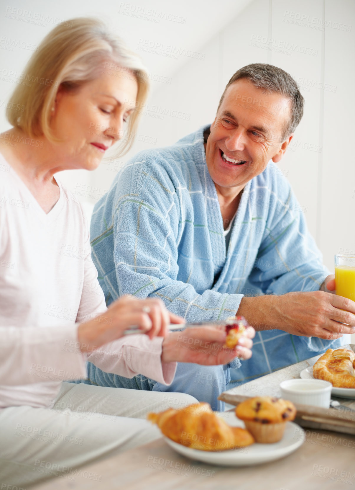 Buy stock photo Senior couple, bedroom and food for diet, breakfast and wellness for retirement health. Mature woman, man and croissant or muffin with fruit juice for romance, nutrition and elderly care or support