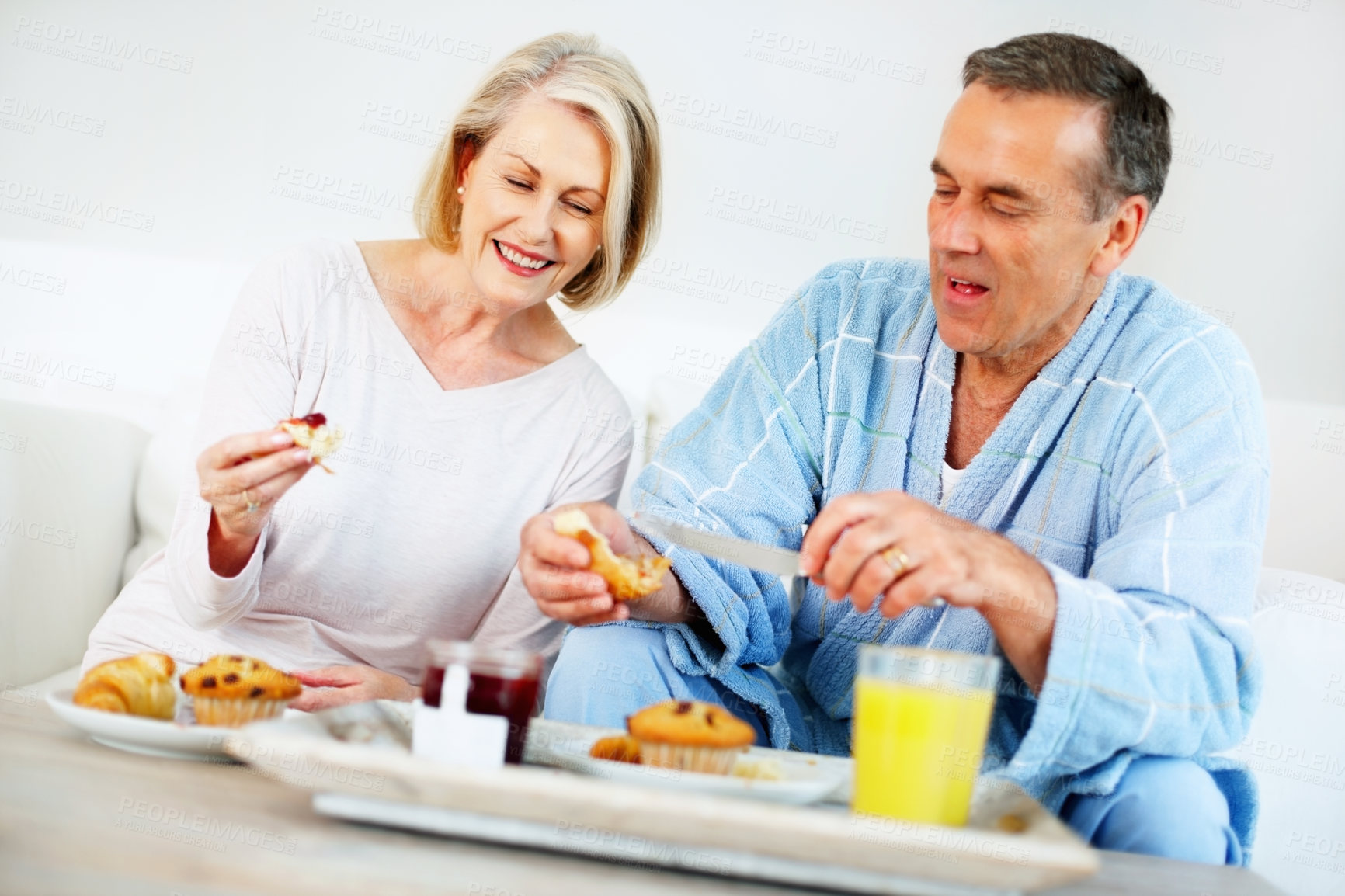 Buy stock photo Senior couple, bedroom and food for nutrition, breakfast and wellness for retirement health. Mature woman, man and croissant or muffin with fruit jam for diet, romance and elderly care or support