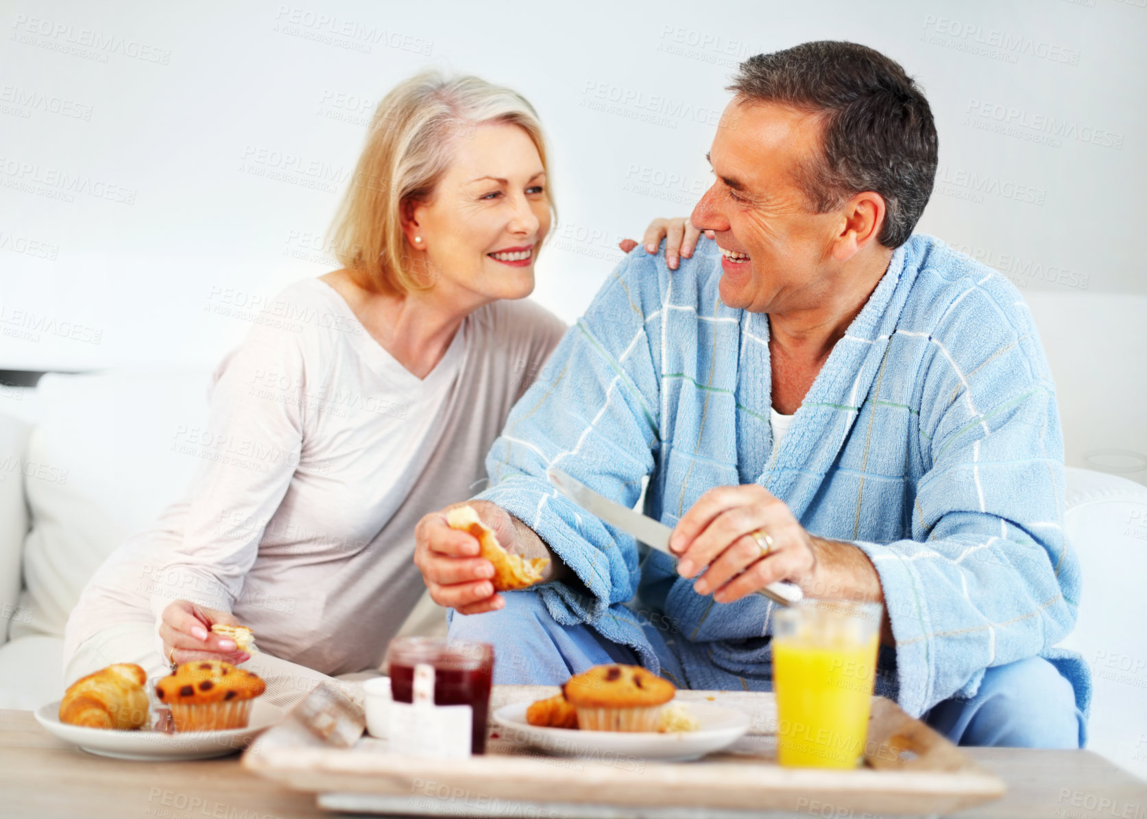 Buy stock photo Senior couple, bedroom and food for wellness, breakfast and nutrition for retirement health. Mature woman, man and croissant or muffin with fruit jam for diet, romance and elderly care or support