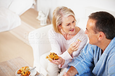 Buy stock photo Senior couple, bedroom and food for feeding, breakfast and nutrition for retirement health. Mature woman, man and croissant or muffin with baked good for diet, romance and elderly wellness or care