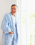 Mature man wearing bathrobe while leaning against wall