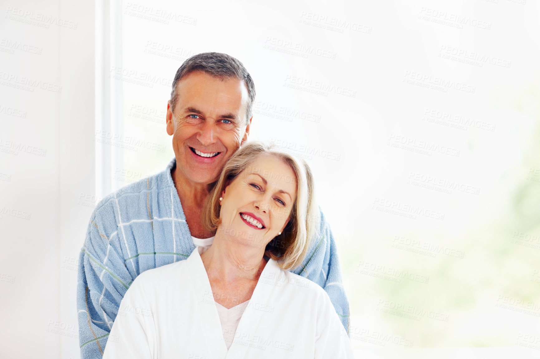 Buy stock photo Portrait, love and window with senior couple, hug and support in living room of house together. Smile, face and trust with happy, mature man and woman bonding while enjoying retirement at home