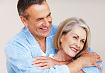 Loving mature man embracing woman against colored background