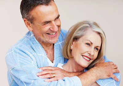 Buy stock photo Mature couple, hug and bonding in home with love for retirement, leisure and wellness in gown. Man, woman and comfort in house for peace, health and relax with smile, happiness and stress relief