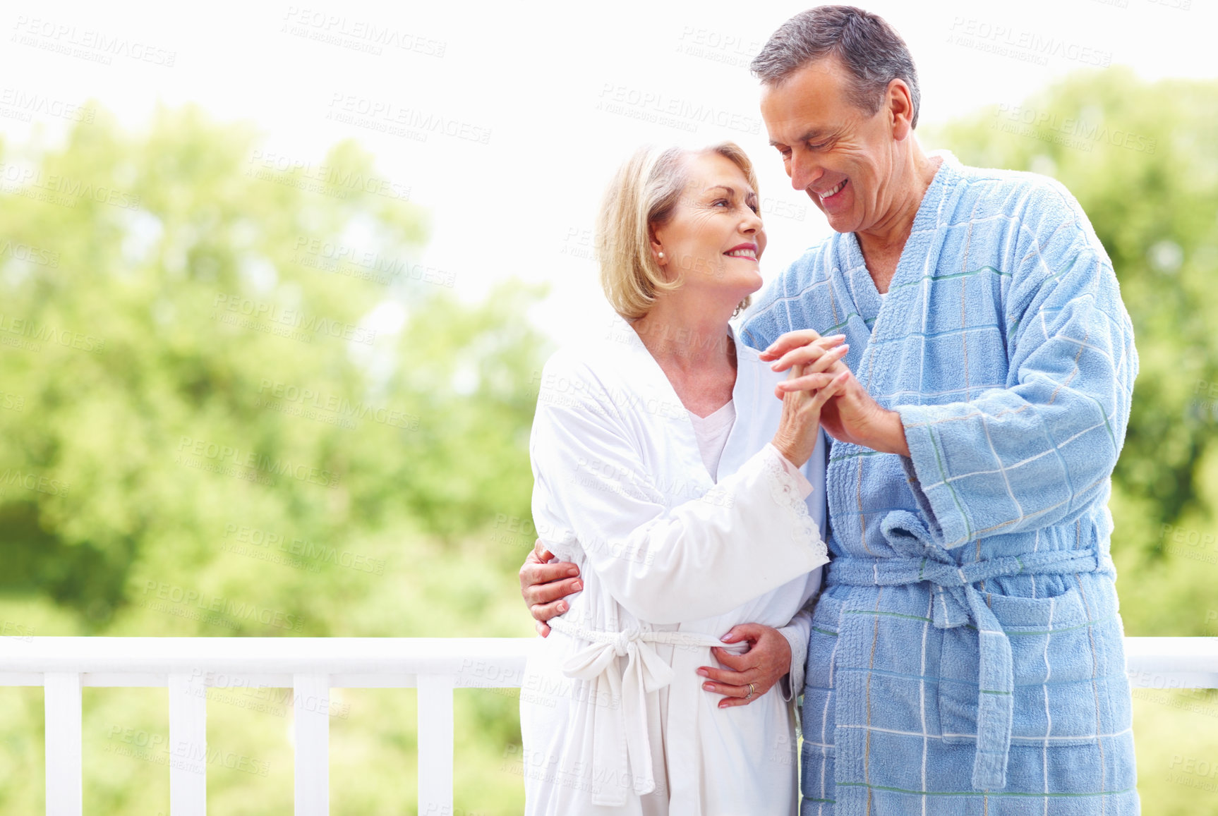 Buy stock photo Senior, couple and bathrobe outdoor on vacation for anniversary trip, romantic holiday and holding hands. Elderly, people and embrace for bonding on honeymoon retreat, retirement and happy on balcony