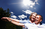 Cheerful mature couple together having fun against sky