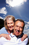 An attractive senior couple having fun against cloudy sky