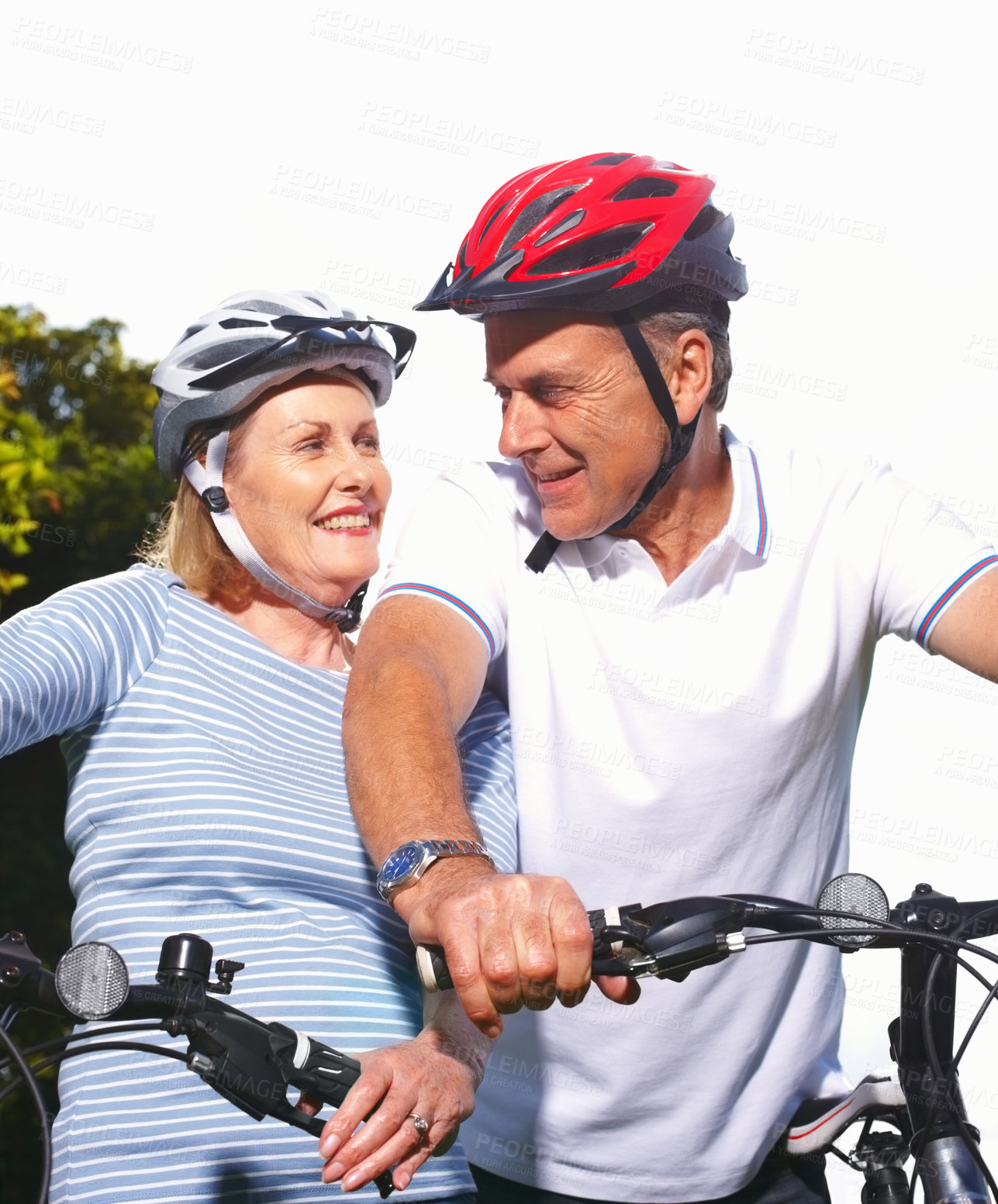 Buy stock photo Portrait of a smiling mature woman and husband riding bicycles on a sunny day