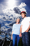 Romantic senior couple standing by bicycle against cloudy sky