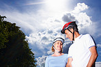 Loving couple wearing protective helmet against cloudy sky