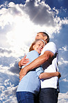 Romantic mature couple hugging each other against cloudy sky