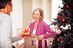 Mature man giving gift to cheerful wife on Christmas festival