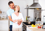 Cheerful mature man embracing wife from behind at kitchen