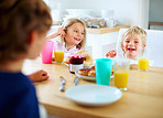 Happy young children having breakfast together