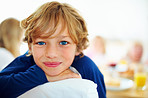 Happy young boy and his family having breakfast in background