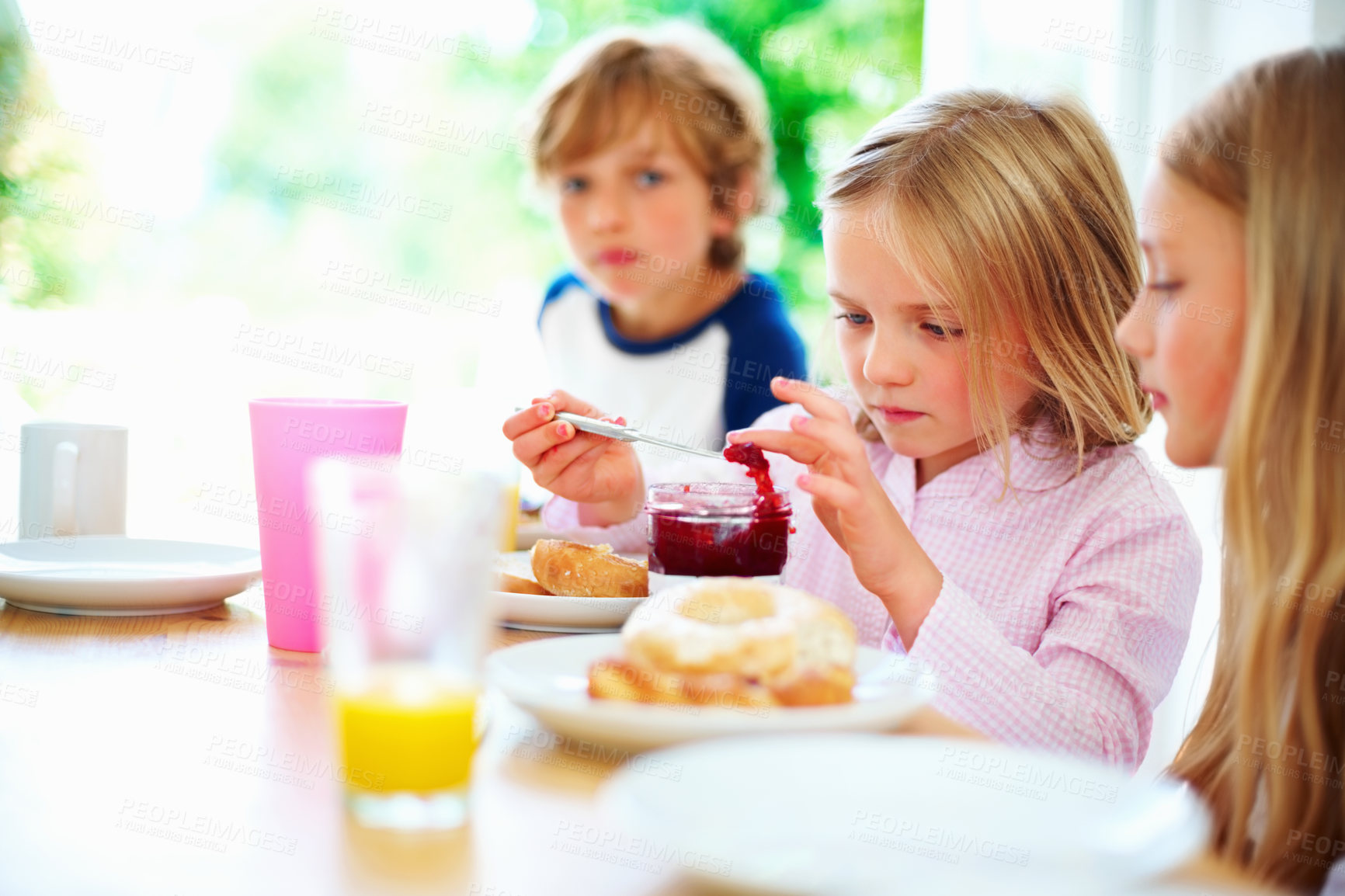 Buy stock photo Family, morning and breakfast jam, children and meal for nutrition, orange juice and bagel. Brother, sisters and enjoying food together for hunger, health and energy for home weekend activities