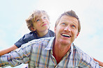 Cheerful mature man with his son having fun together against sky