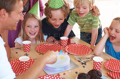 Buy stock photo Happy birthday, cake decoration and celebration by table, party and fun in home with wellness. Father, children and excited family by muffins, candles and hats with love for special event in house