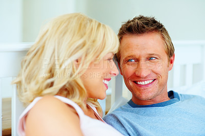 Buy stock photo Couple, face and smile in bed of home for love, care and relax for holiday, break and wake up together. Man, woman and bedroom in morning for happy relationship, freedom and bonding with partner 