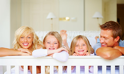 Buy stock photo Portrait, happy and a family lying on a bed together while in their home on a weekend morning. Face, love and the smile of a mom, dad and children in the bedroom of an apartment to relax for bonding