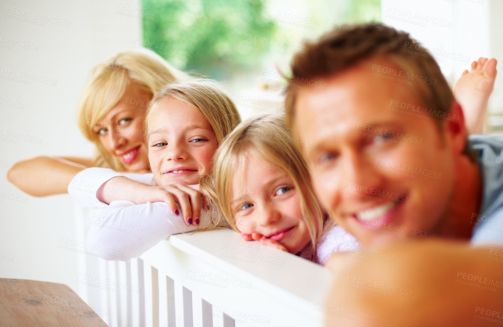 Buy stock photo Portrait, smile and a family lying in a bedroom together while in their home on a weekend morning. Face, love and a happy father, mother and children on the bed of an apartment to relax for bonding