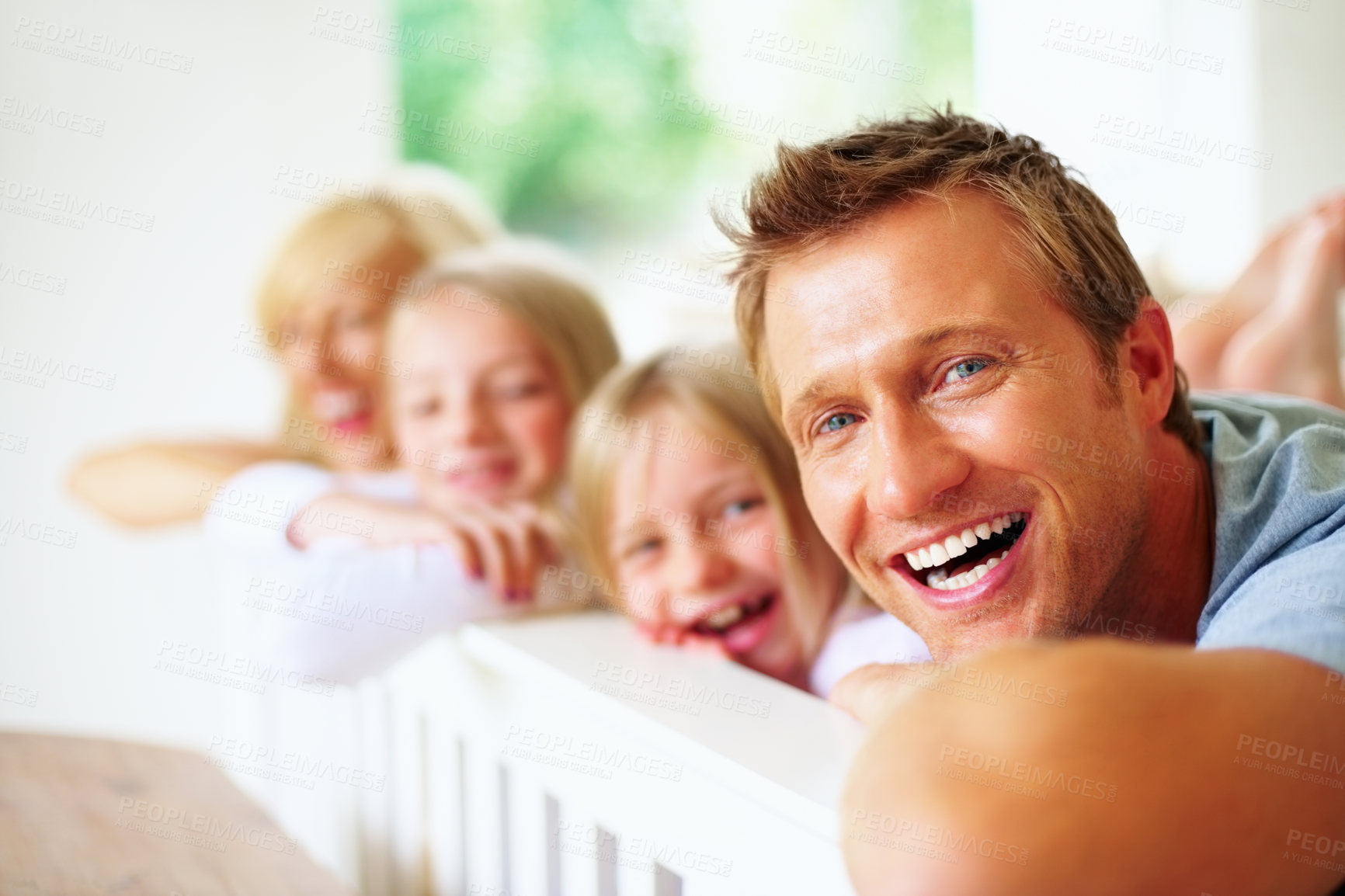 Buy stock photo Portrait, smile and a family laughing on a bed together while in their home on a weekend morning. Face, love and a funny father, mother and kids in the bedroom of an apartment to relax for bonding