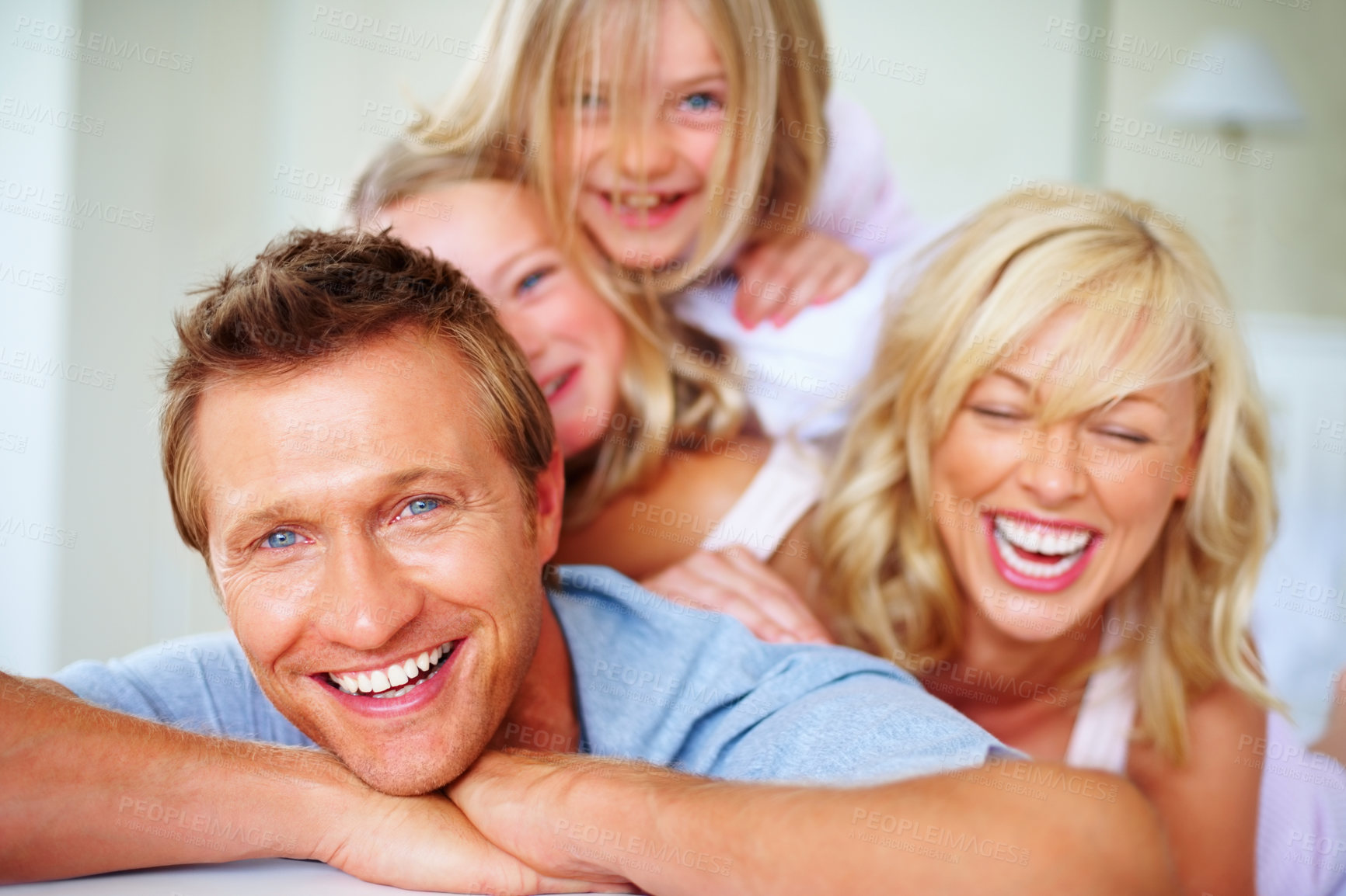 Buy stock photo Portrait, love and a family laughing on a bed together while in the home on a weekend morning. Face, smile and a funny father, mother and children in the bedroom of an apartment to relax for bonding