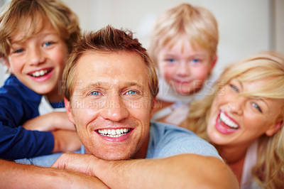 Buy stock photo Portrait, smile and a happy family on a bed together while in the home on a weekend morning. Face, love or funny with a dad, mom and kids laughing in the bedroom of an apartment to relax for bonding