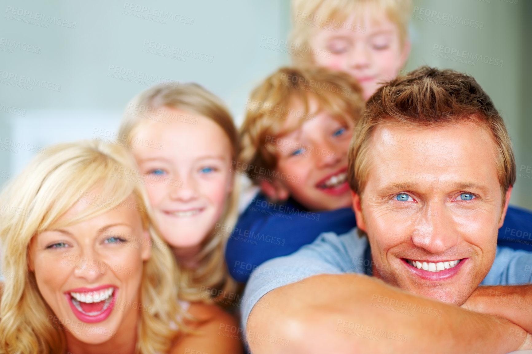 Buy stock photo Portrait, funny and a happy family on a bed together while in the home on a weekend morning. Face, smile or love with a father, mother and children in the bedroom of an apartment to relax for bonding