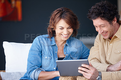 Buy stock photo Shot of a husband and wife using a digital tablet together at home