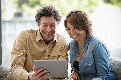 Buy stock photo Shot of a husband and wife using a digital tablet together at home