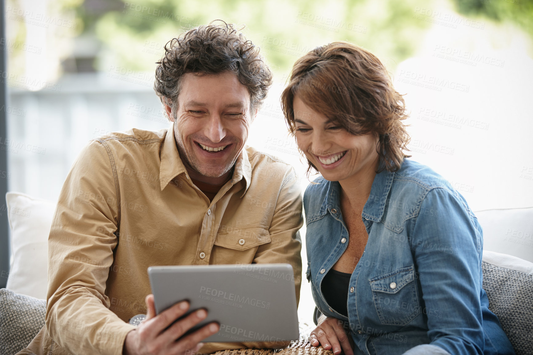 Buy stock photo Shot of a husband and wife using a digital tablet together at home