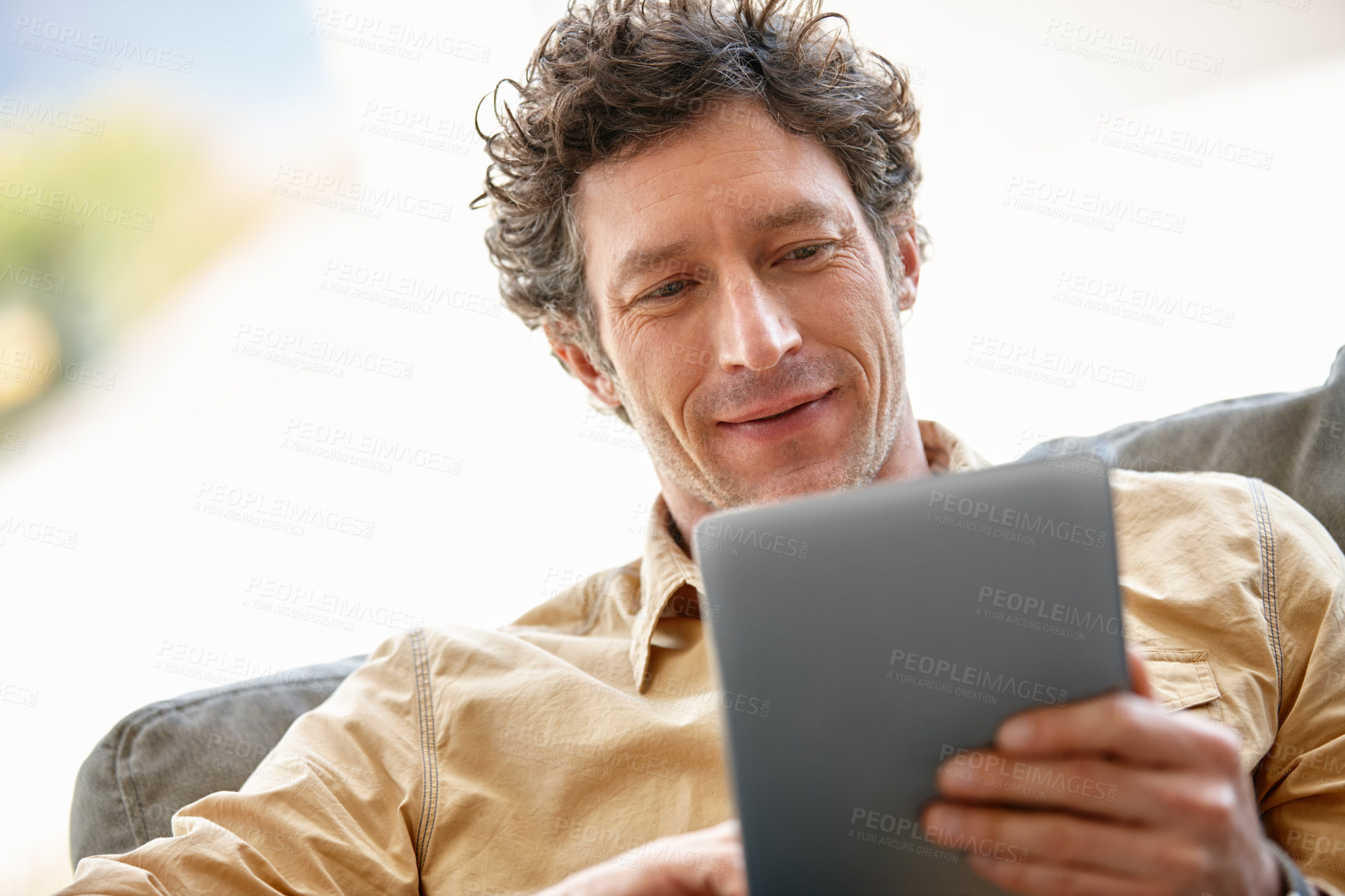 Buy stock photo Shot of a mature man using a digital tablet on the sofa at home