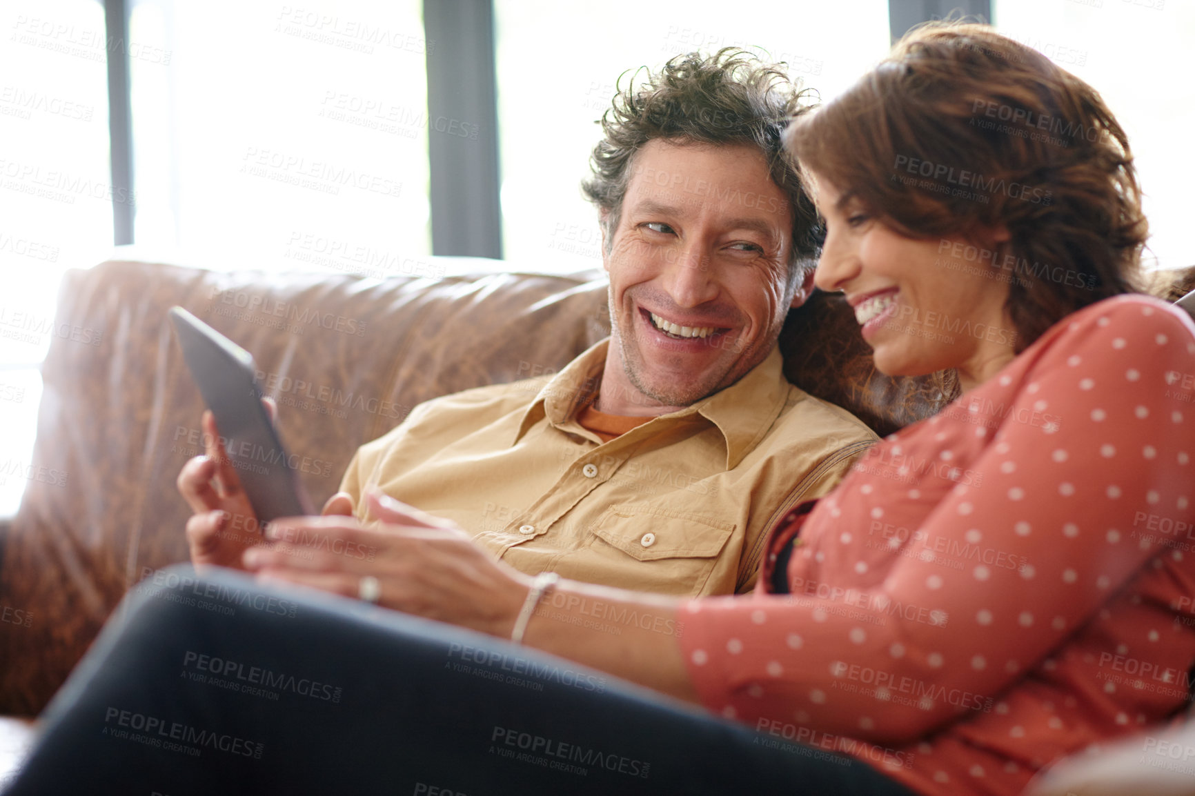 Buy stock photo Shot of a husband and wife using a digital tablet together at home