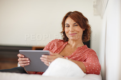 Buy stock photo Shot of a mature woman using a digital tablet on the sofa at home