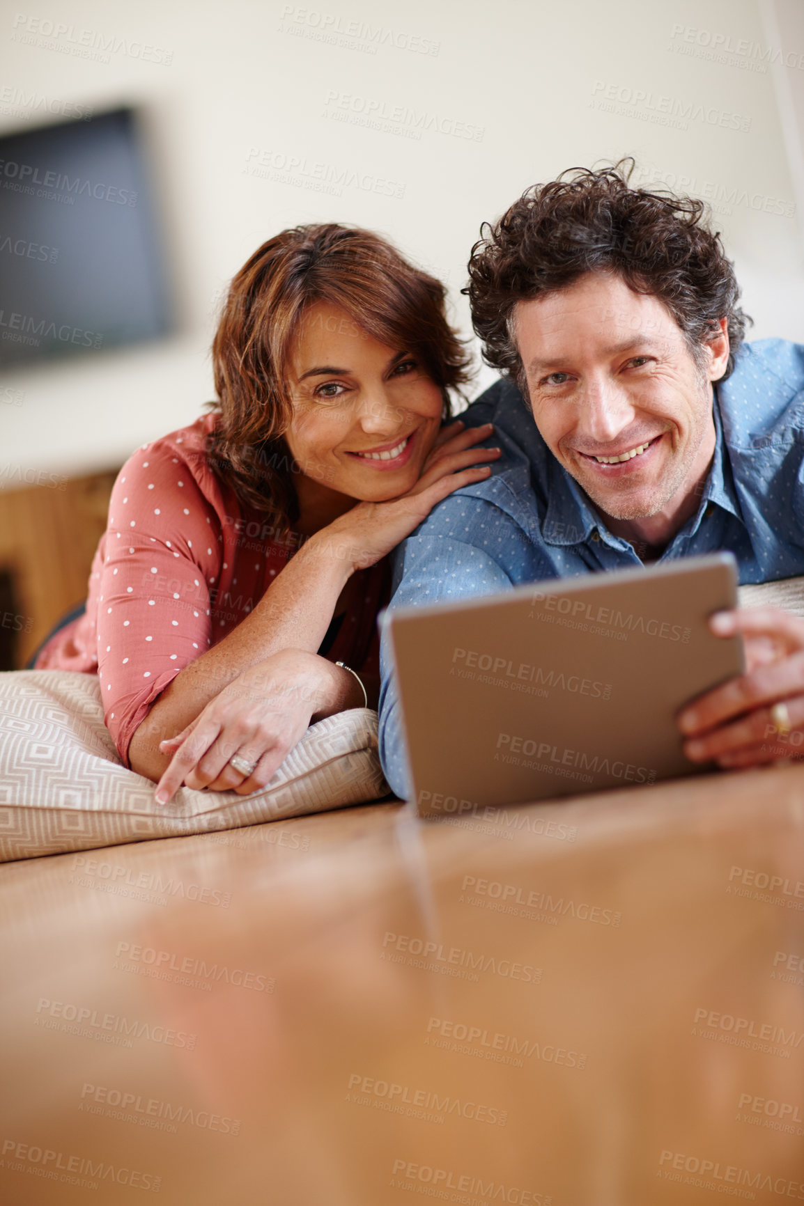 Buy stock photo Shot of a husband and wife using a digital tablet together at home