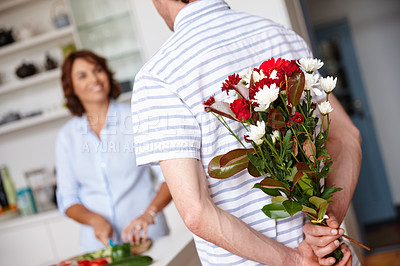 Buy stock photo Shot of a husband surprising his wife with a bunch of flowers at home