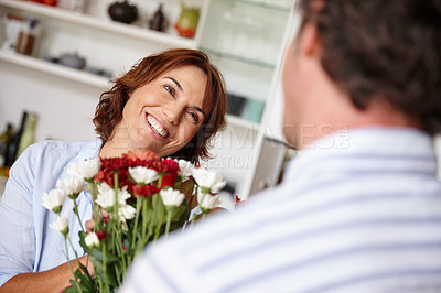 Buy stock photo Shot of a husband giving his wife a bunch of flowers at home