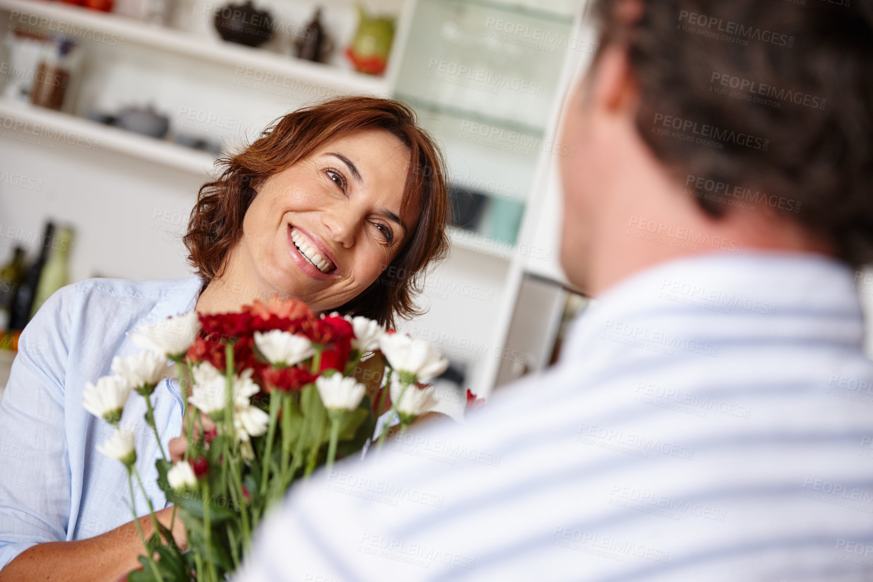 Buy stock photo Shot of a husband giving his wife a bunch of flowers at home