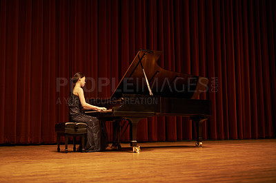 Buy stock photo Shot of a young woman playing the piano during a musical concert