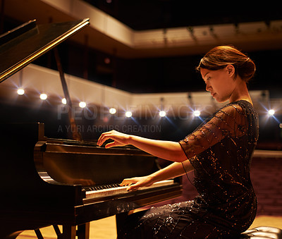 Buy stock photo Shot of a young woman playing the piano during a musical concert