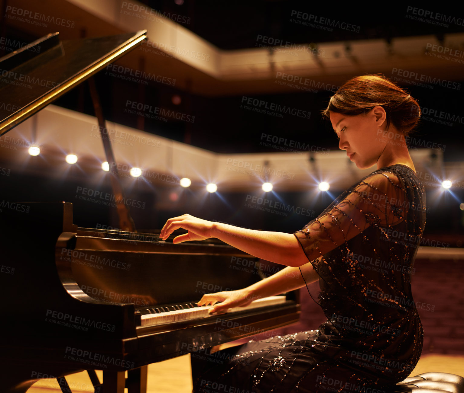 Buy stock photo Shot of a young woman playing the piano during a musical concert