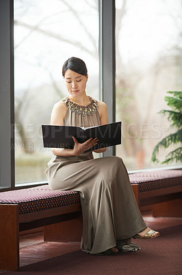 Buy stock photo Shot of an elegantly dressed young woman reading through a folder