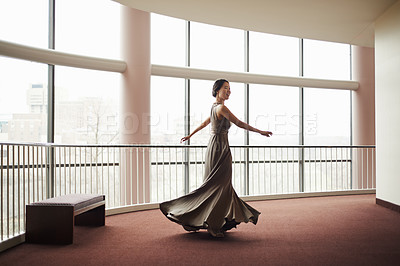 Buy stock photo Shot of an elegantly dressed young woman dancing through a  large hallway