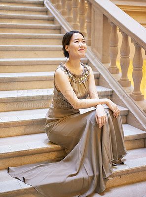 Buy stock photo Shot of an elegantly dressed young woman sitting on a staircase