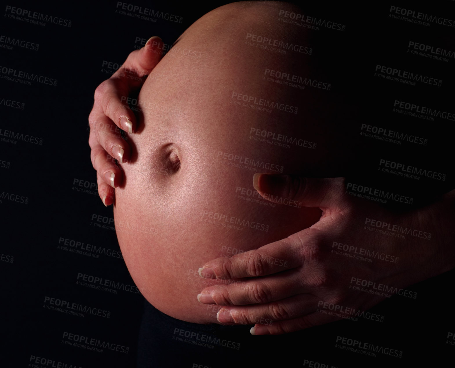 Buy stock photo Detail shot of a pregnant woman holding exposed belly against black background