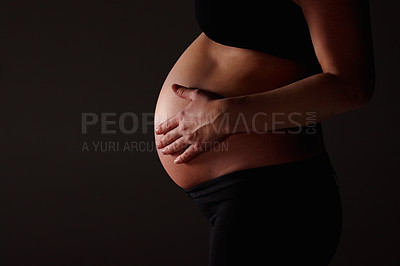 Buy stock photo Mid section of a pregnant woman expecting a baby against black - copyspace