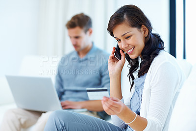 Buy stock photo Beautiful woman shopping over phone with credit card while man using laptop in background