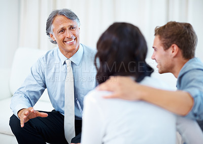 Buy stock photo Mature financial planner discussing with young couple at home