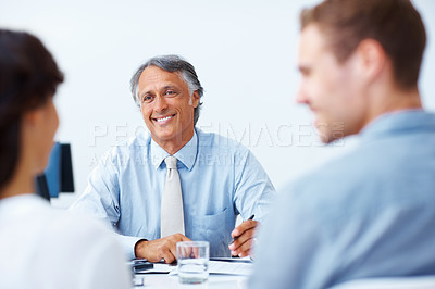 Buy stock photo Smiling mature advisor discussing with young couple in office